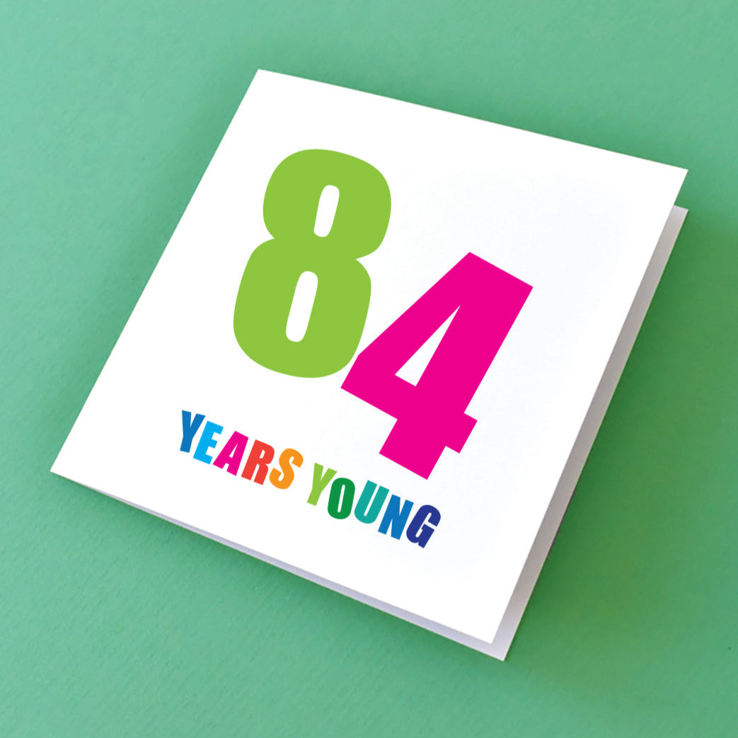 Birthday card for him that reads 84 Years Young in bold, fun colourful text.