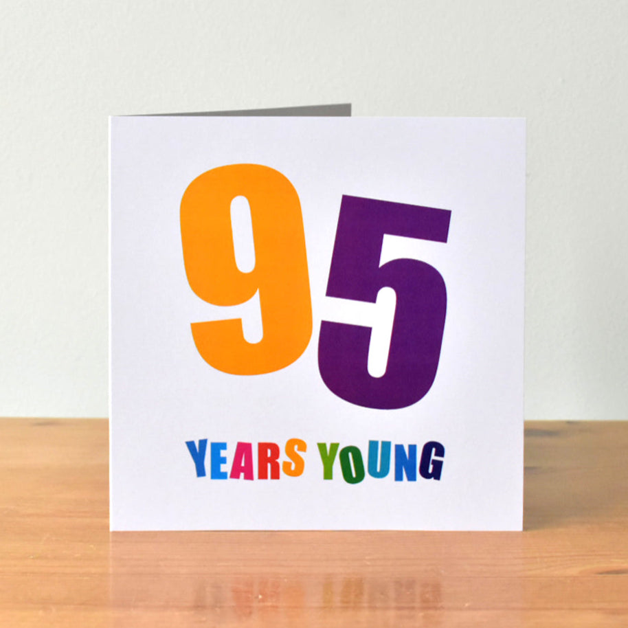 Square white birthday card with the large, bold number "95" prominently displayed. Each digit of "95" is at a different angle and in a different bold colour, amber and purple. The words "Years Young" are written below, with each letter in a different bold colour.