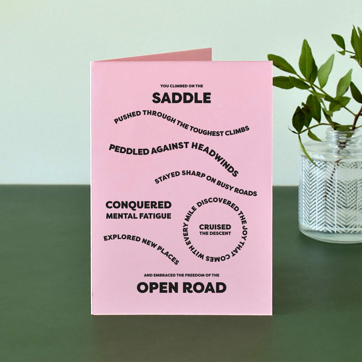 Pink A6 card with bold black text that reads "You climbed on the saddle, pushed through the toughest climbs, peddled against headwinds, stayed sharp on busy roads, conquered mental fatigue, discovered the joy that comes with every mile, cruised the descent, explored new places and embraced the freedom of the open road."