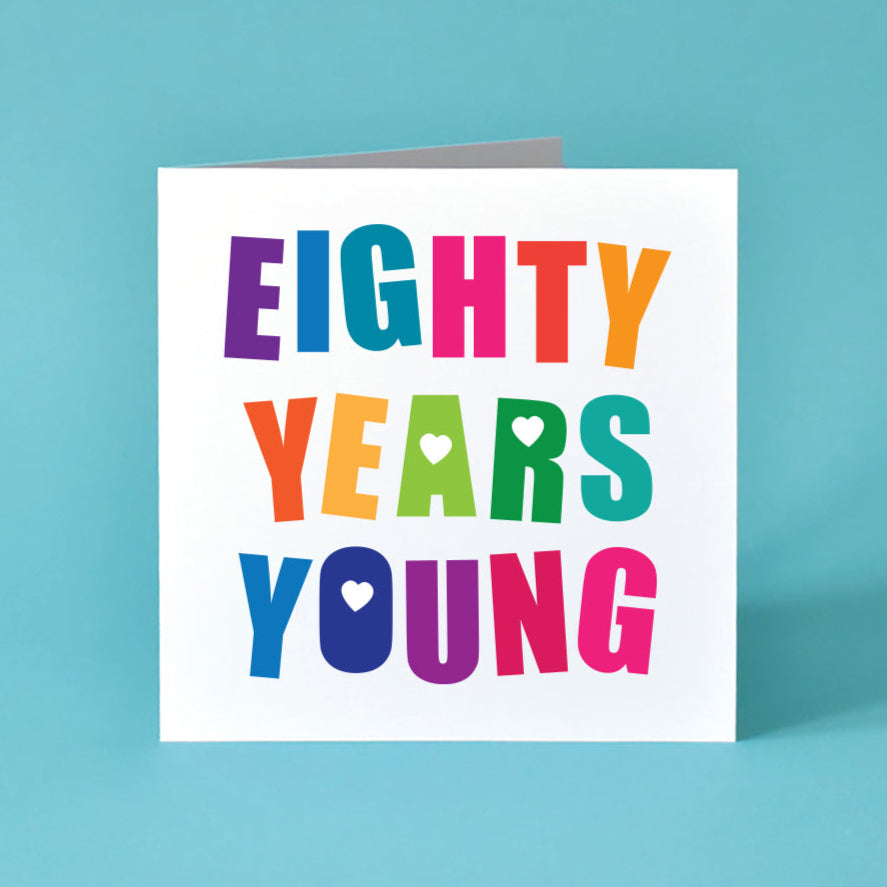 Square white Card with the Birthday message Eighty Years Young written boldly across the card over 3 lines. Each letter is a different bright colour and those with holes in are filled with a heart.