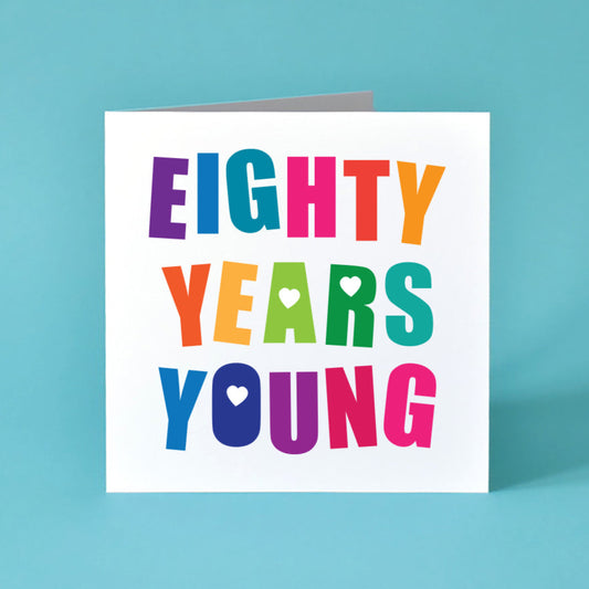 Square white Card with the Birthday message Eighty Years Young written boldly across the card over 3 lines. Each letter is a different bright colour and those with holes in are filled with a heart.