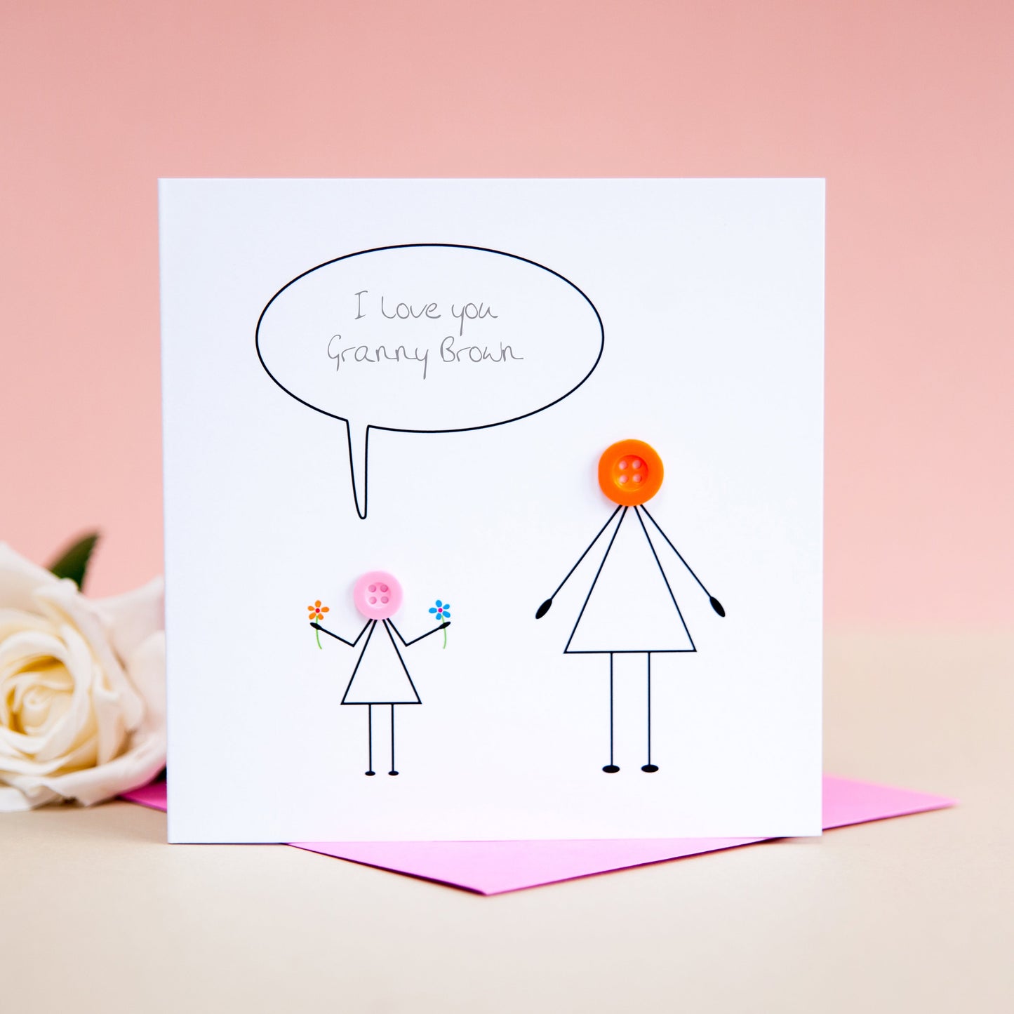 Detailed view of vibrant 3D button heads on a personalised stick-figure family card, showing a mother figure with a little girl.