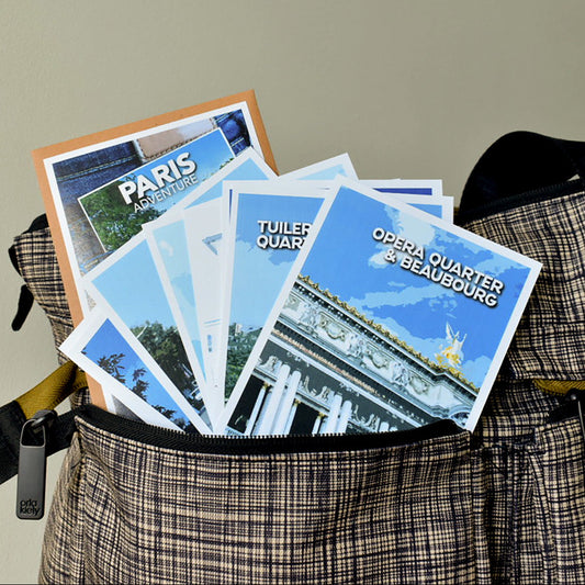 Paris Pocket Travel Guide set showing 7 illustrated A6 arrondissement guides, a Food Bingo card, and a "Save the Date" surprise card.