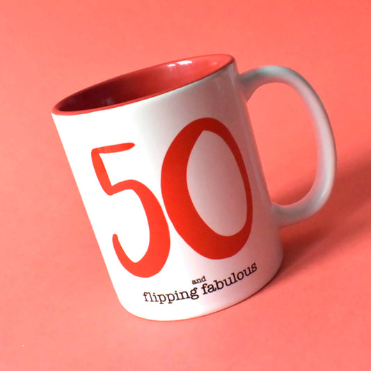 White ceramic mug with a red interior. Features a large red "50" and black text "and flipping fabulous." Ideal 50th birthday gift.