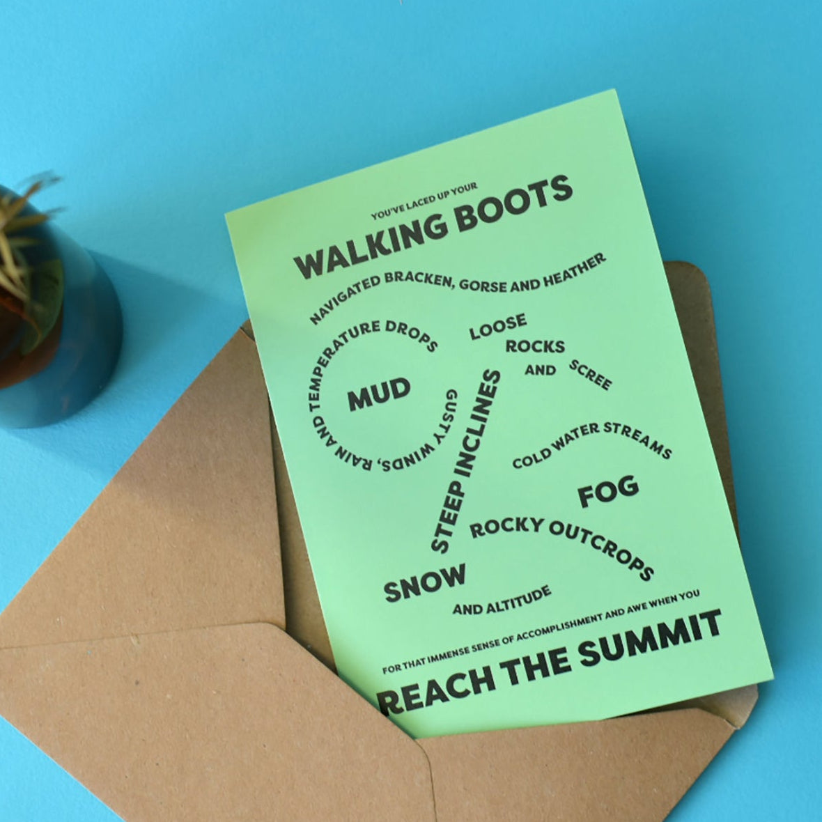 Green A6 card with bold, black text that reads ""You've laced up your walking boots, navigated bracken, gorse and heather, loose rocks and scree, gusty winds, rain and temperature drops, mud, steep inclines, cold water streams, fog, rocky outcrops, snow and altitude for that immense sense of accomplishment and awe when you reach the summit."