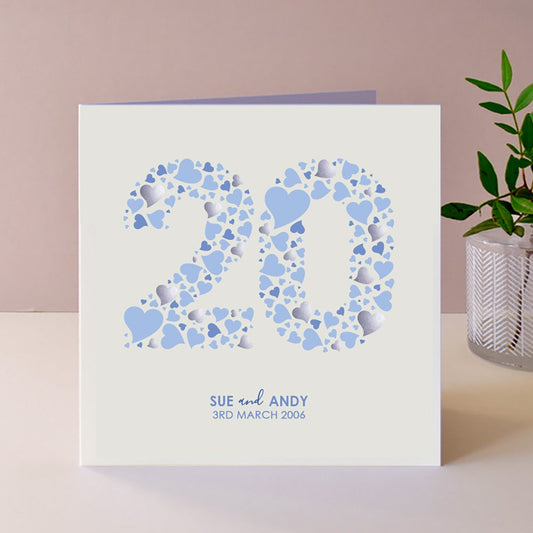 White anniversary card with lots of blue hearts forming the number 20. Underneath are the names of the couple alongside their wedding date.