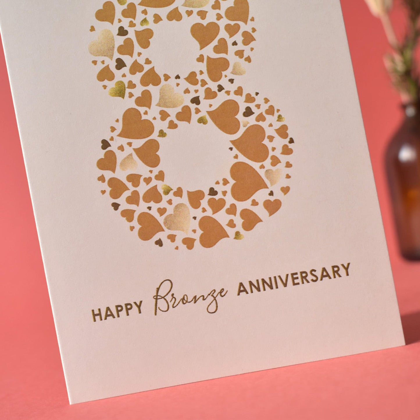 Close up of mixed typography that reads Happy Bronze Anniversary and number 8 made from a collection of love hearts in different sizes and shades of bronze.