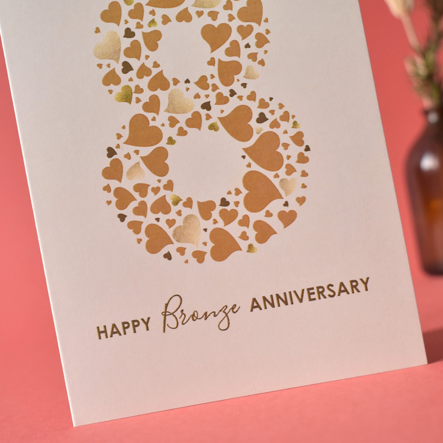 Close up of mixed typography that reads Happy Bronze Anniversary and number 8 made from a collection of love hearts in different sizes and shades of bronze.