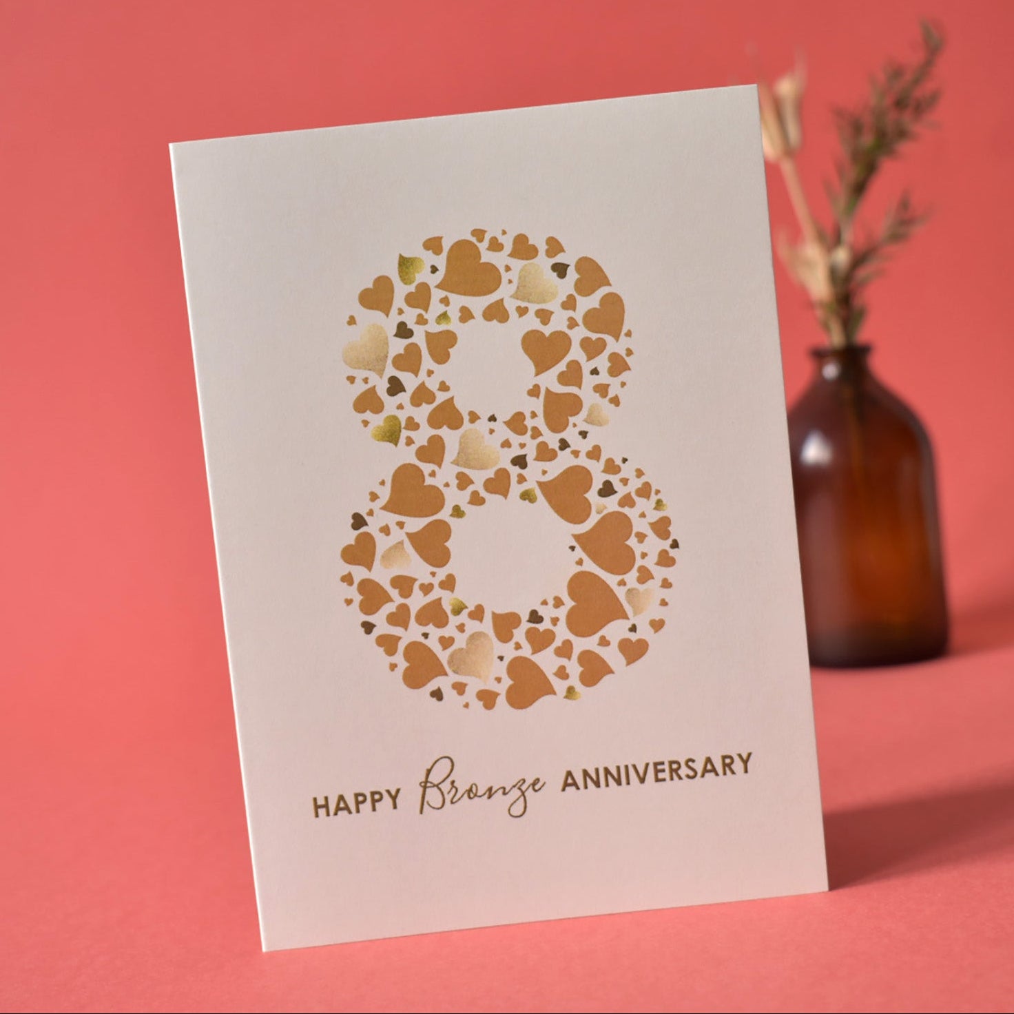 A6 cream greetings card with a large 8 made up of love hearts in shades of bronze. The words Happy Bronze Anniversary are underneath the number 8.