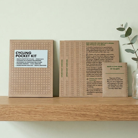 Cycling Pocket Kit in a patterned kraft wallet showing double-sided cyclist training cards and Epsom salts packet.