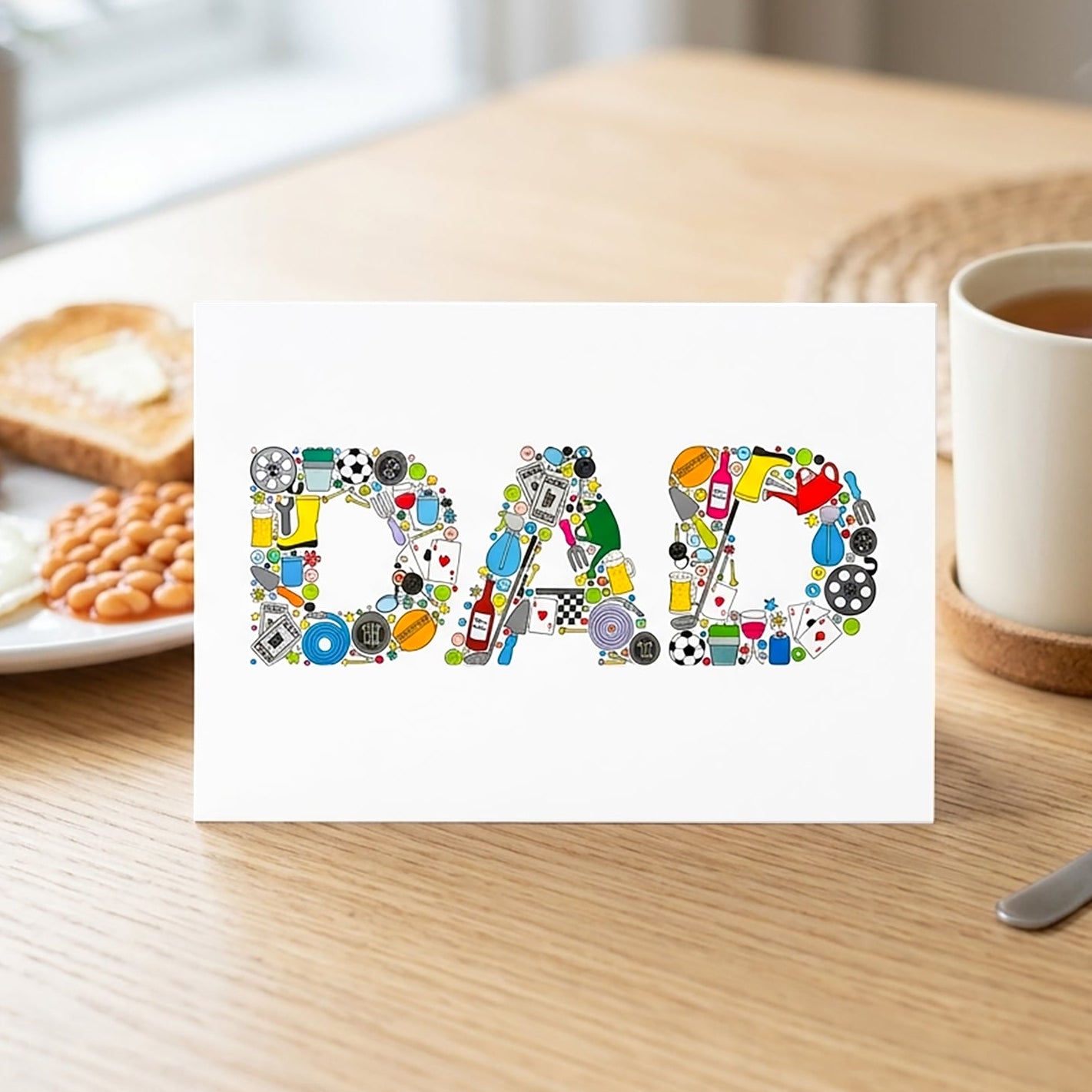 Colorful 'DAD' card on a table with breakfast and a mug.
