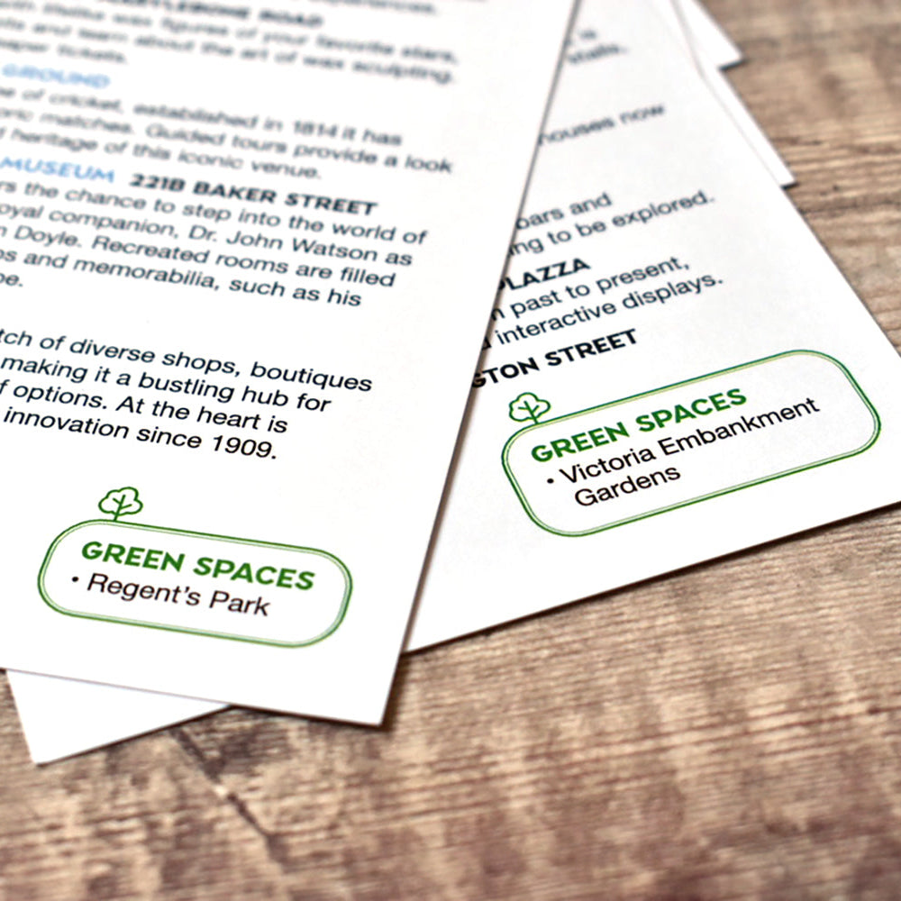 Two printed paper cards with text and green highlighted sections, placed on a wooden surface.