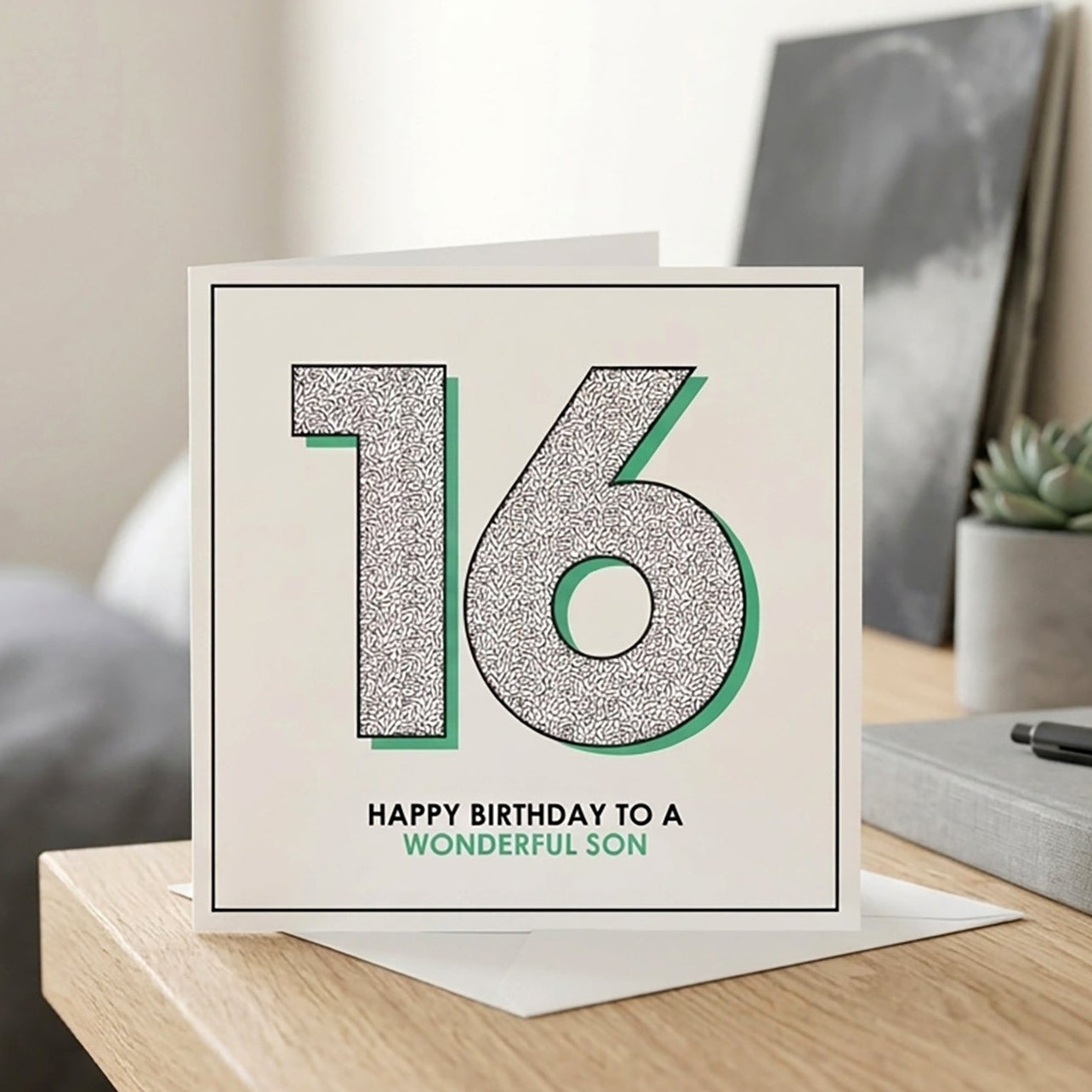 Greeting card with '16 - Happy Birthday to a wonderful son' on a table in a room.