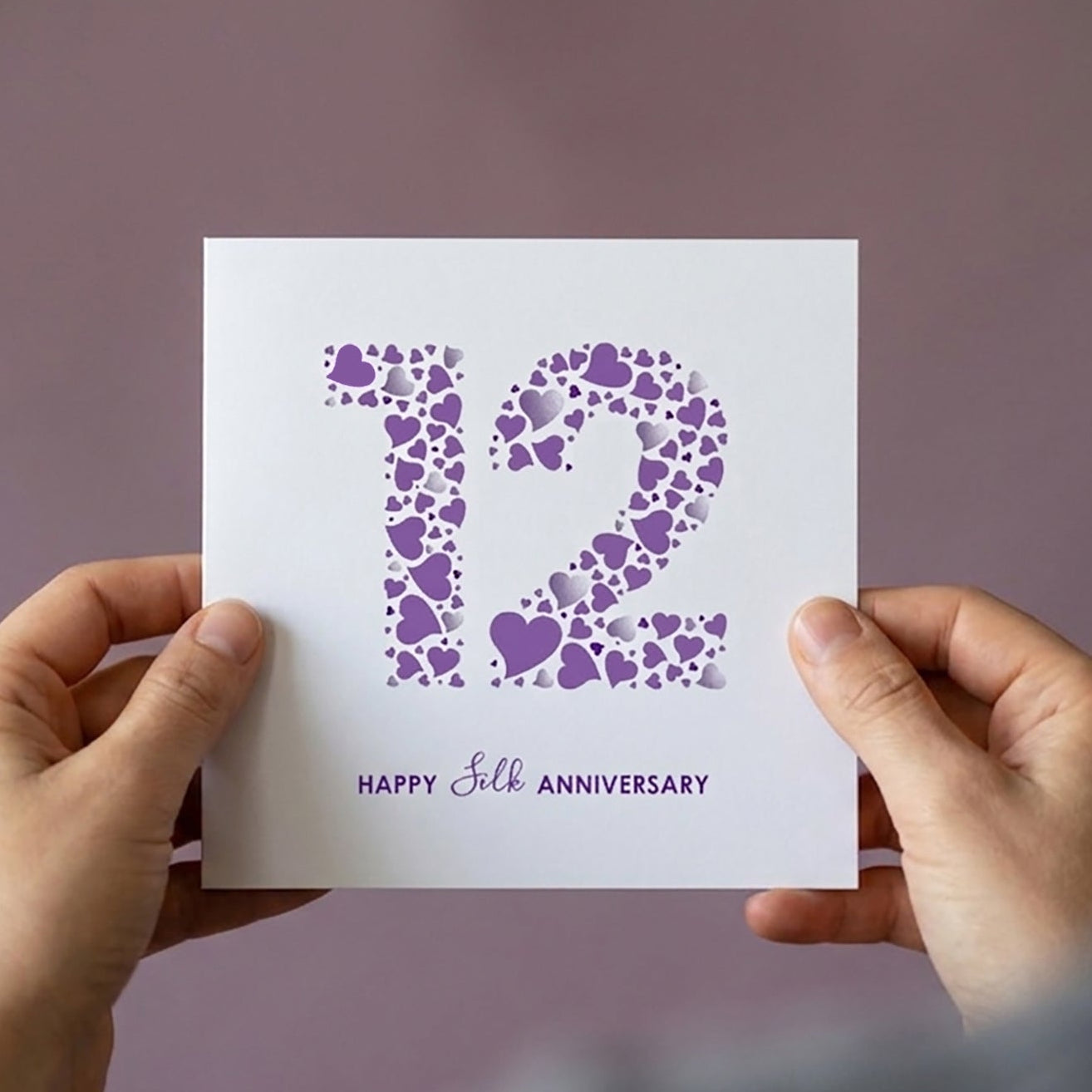 Person holding a card for a 12th Anniversary with a large nubmer 12 and the message Happy Silk Anniversary' text .