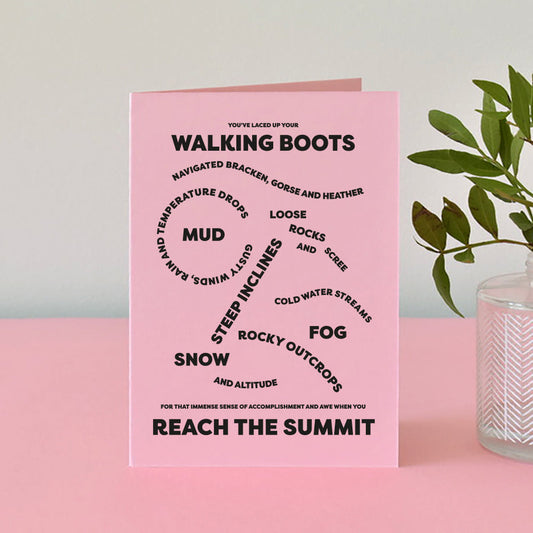 Pink card with bold, black text that reads The wording on the card reads "You've laced up your walking boots, navigated bracken, gorse and heather, loose rocks and scree, gusty winds, rain and temperature drops, mud, steep inclines, cold water streams, fog, rocky outcrops, snow and altitude for that immense sense of accomplishment and awe when you reach the summit."