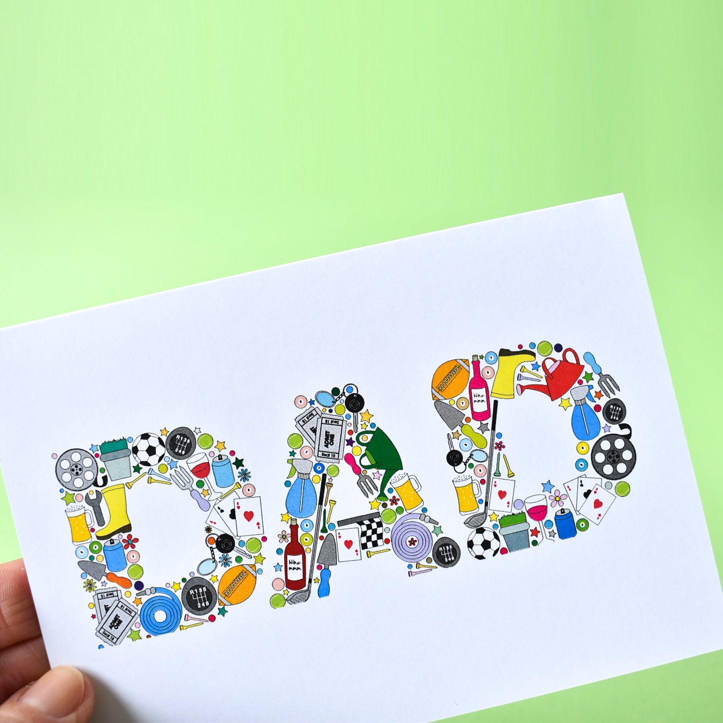 Close up of letters that form the word DAD. The D is made from illustrations assembled together. The illustrations are of a film reel, a plant in a plant pot, a football, car gears and keys, a trowel, can of fizzy pop, playing card, a rugby ball, a garden hose, cinema tickers, snooker balls and tennis balls.