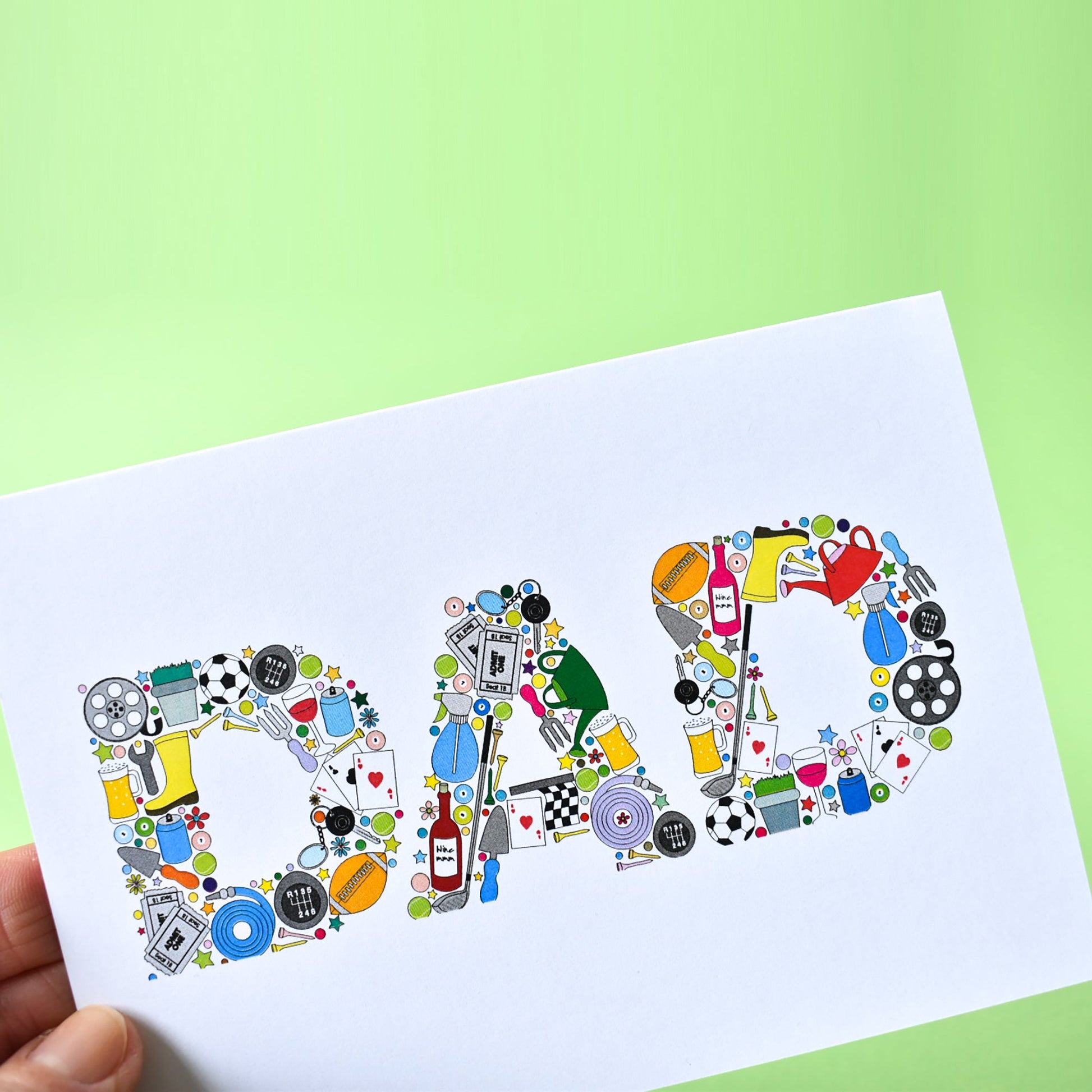 Close up of letters that form the word DAD. The D is made from illustrations assembled together. The illustrations are of a film reel, a plant in a plant pot, a football, car gears and keys, a trowel, can of fizzy pop, playing card, a rugby ball, a garden hose, cinema tickers, snooker balls and tennis balls.