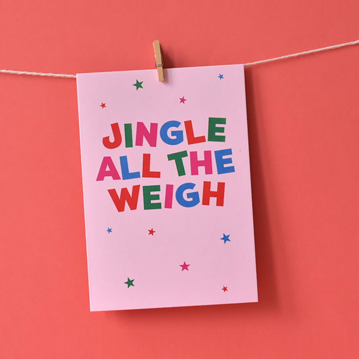 Christmas Card with 'Jingle All The Weigh' text hanging on a string against a red background