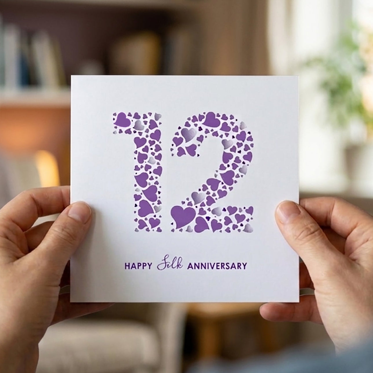 Elegant typography and heart pattern cards for a 12-year anniversary card. The text reads 'Happy Silk Anniversary' in clean, modern purple lettering beneath the detailed heart-filled number 12.