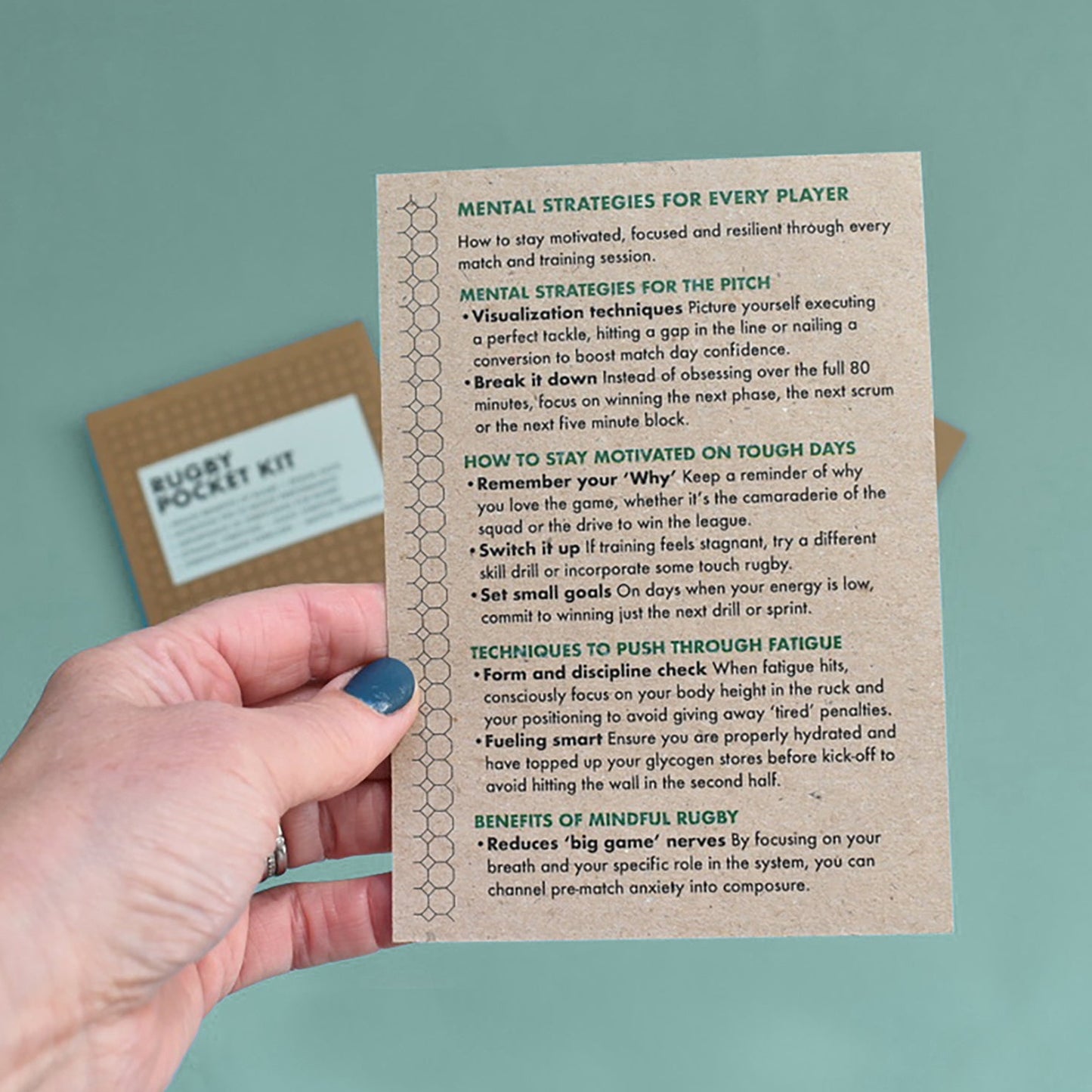 Hand holding a leaflet with 'Mental Strategies for Every Player' for rugby players.