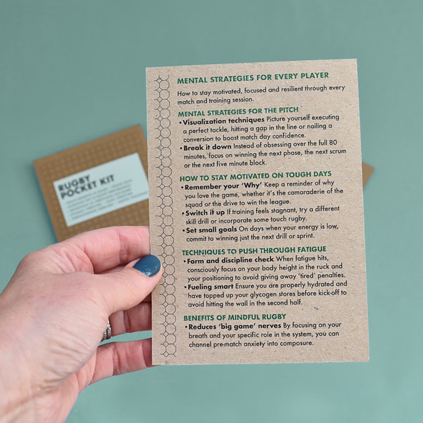 Hand holding a leaflet with 'Mental Strategies for Every Player' for rugby players.