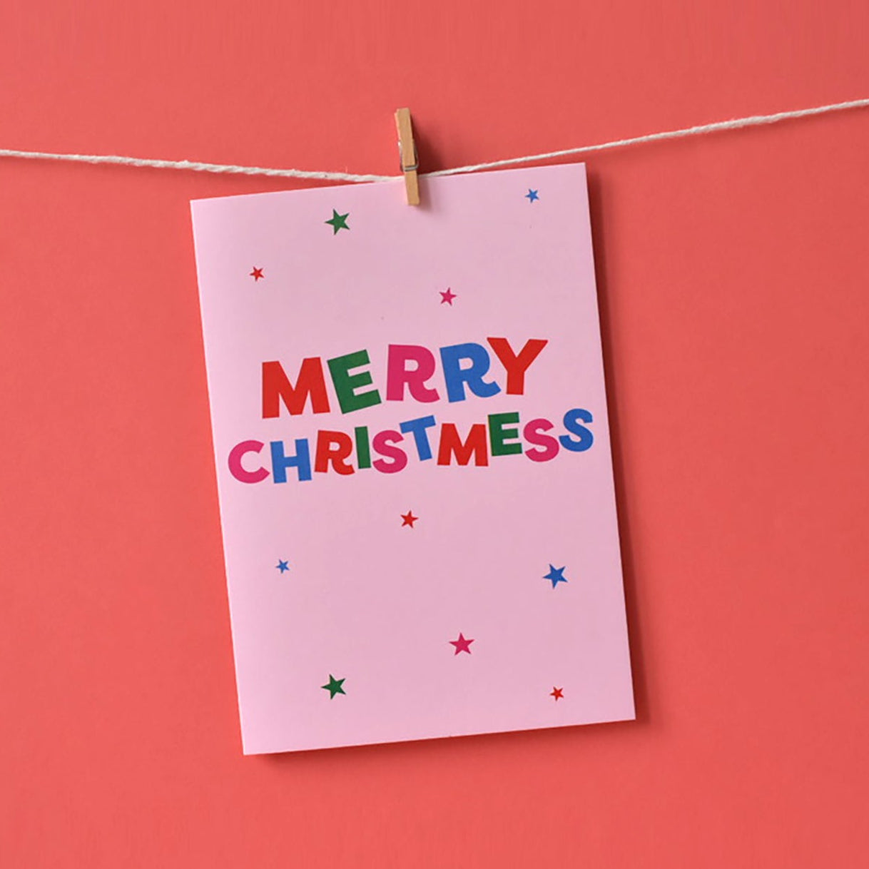 Pink Christmas card with 'MERRY CHRISTMESS' text in red, green, pink and blue.