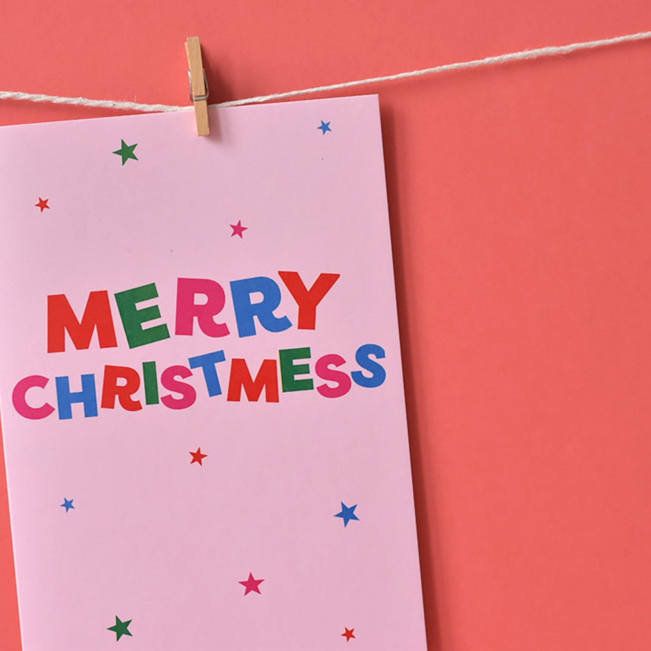 Colourful 'Merry Christmess' card on a pink background