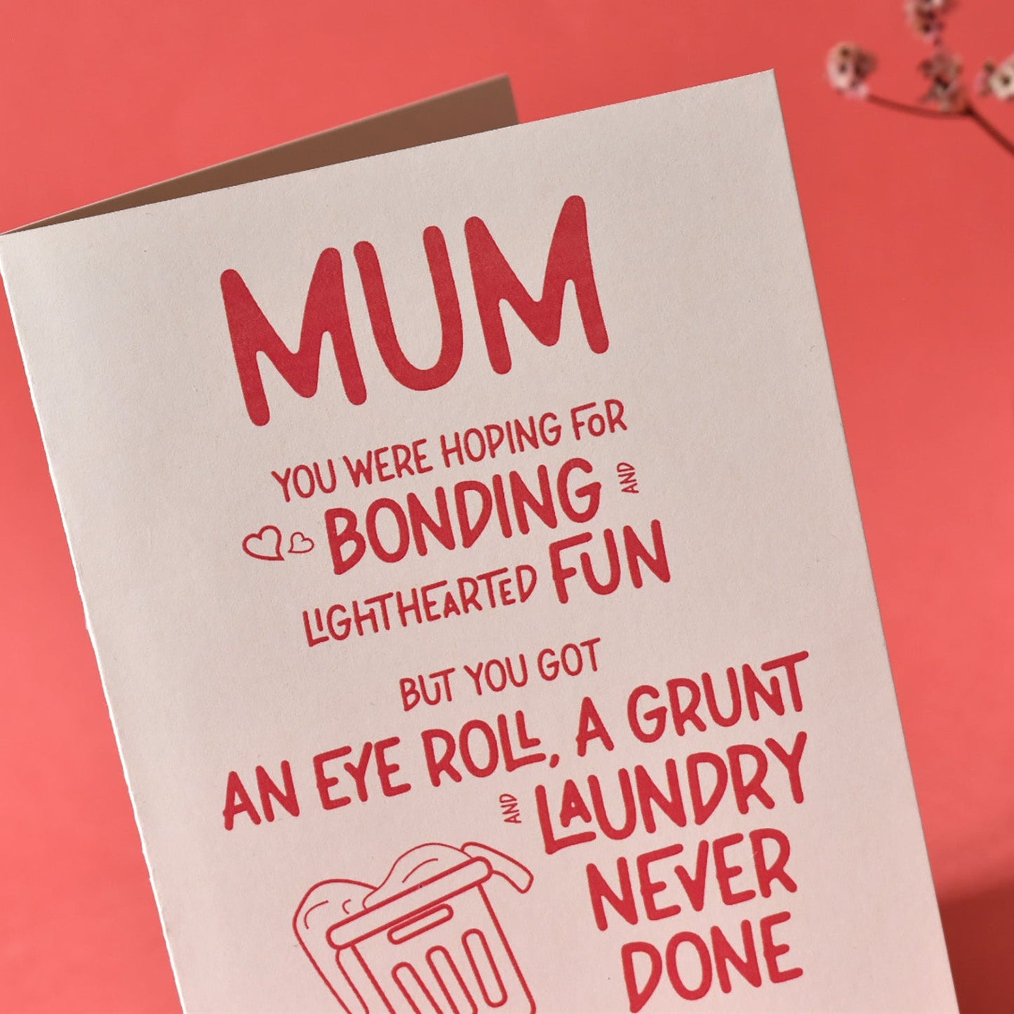 Close-up of humorous "Mum you were hoping for bonding" text on a cream greeting card with vibrant red lettering.
