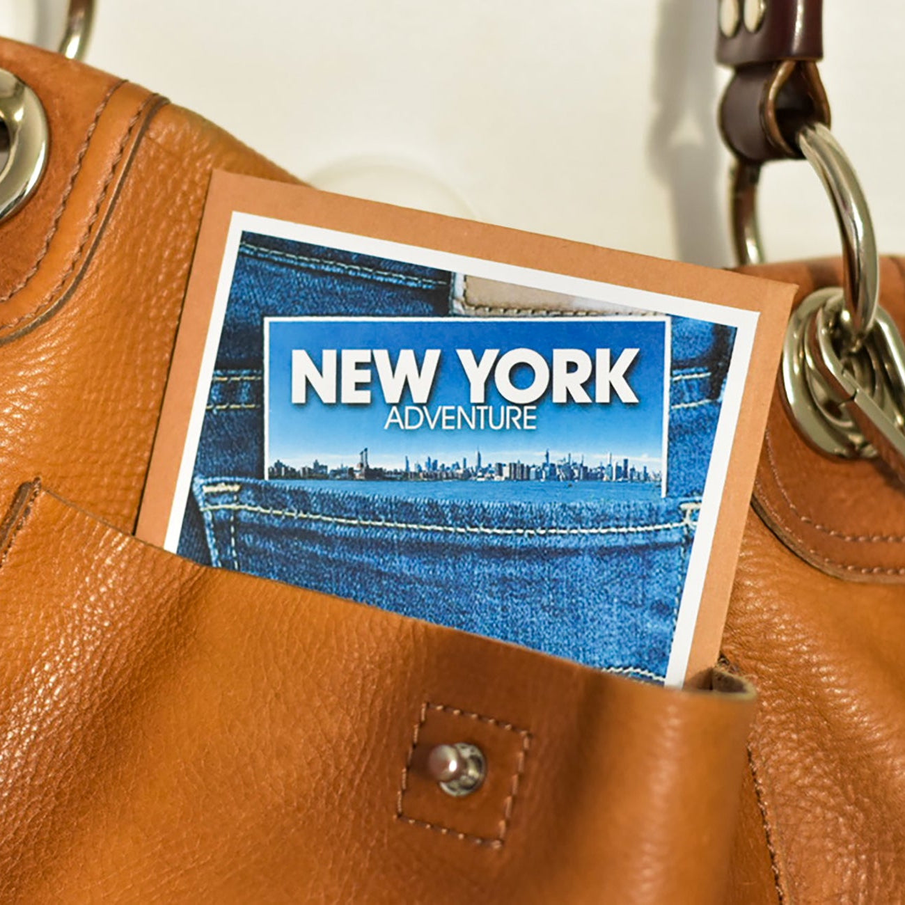 Brown leather handbag with a 'New York Adventure' wallet inside the pocket.
