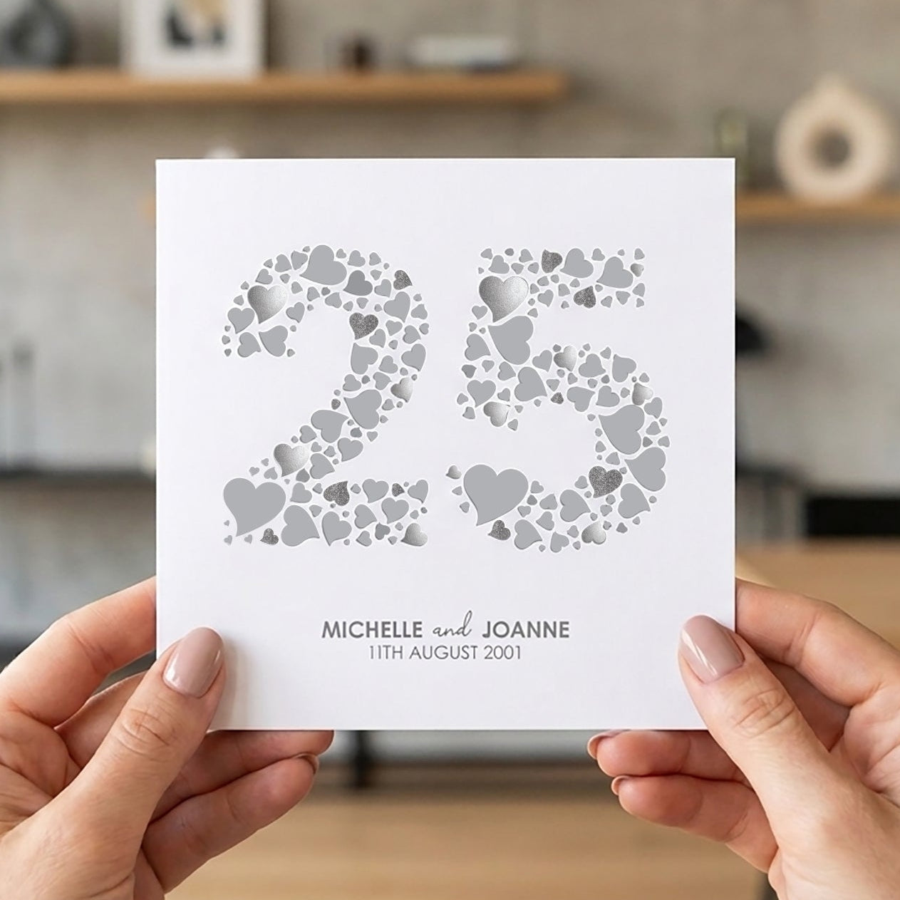 Person holding a card with '25th wedding anniversary card'.
