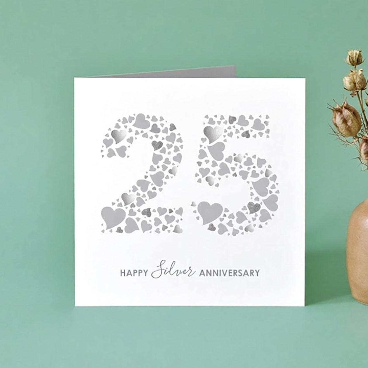 A silver wedding anniversary card with the number 25 made from love hearts on a green background, with a greeting of 'Happy Silver Anniversary'.