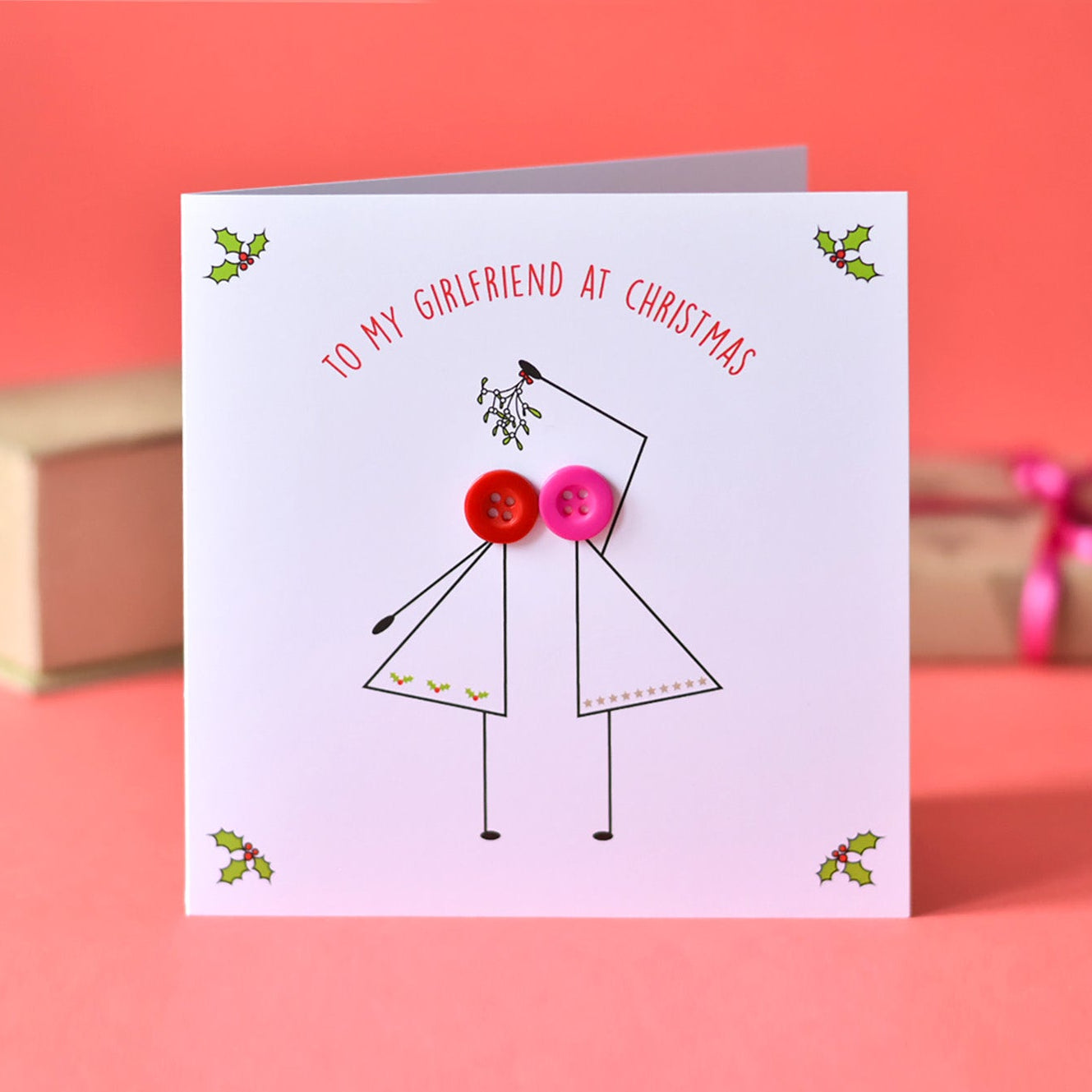 Greeting card with a design of two people holding hands with buttons instead of heads, on a pink background.