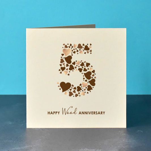 Square cream card with a large 5 in the centre. The 5 is made from a collection of brown love hearts some with a printed shimmer. Underneath the number 5 is the message "Happy Wood Anniversary".