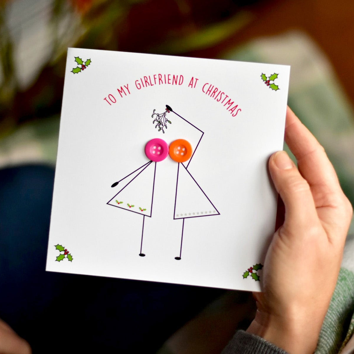 To My Girlfriend at Christmas Card with 2 stick figure women with coloured buttons heads. The ladies are kissing under mistletoe.
